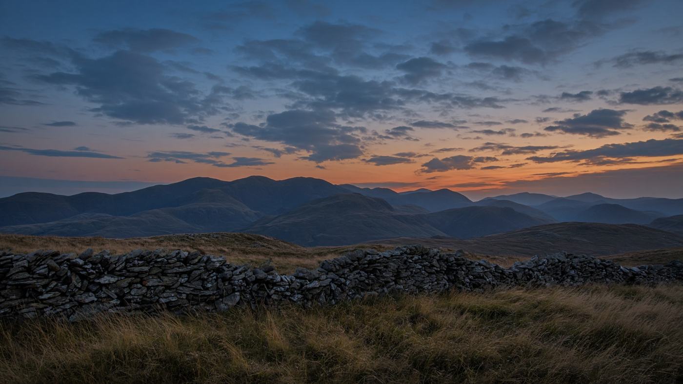 Lake District fells at dusk with a dry-stone wall in the foreground